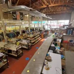 Inside of a thrift store with different kinds of thrift items, clothes, crockery and books