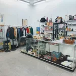 Inside of a thrift store with different kinds of thrift items, clothes, crockery and books