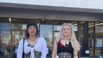 Two women stand smiling in front of Beacons Thrift Shop. Both wear stylish outfits; one in a layered top and pants, the other in a black dress with silver accessories. Text at the bottom reads: “Campus Couture at Cal State Long Beach.”.